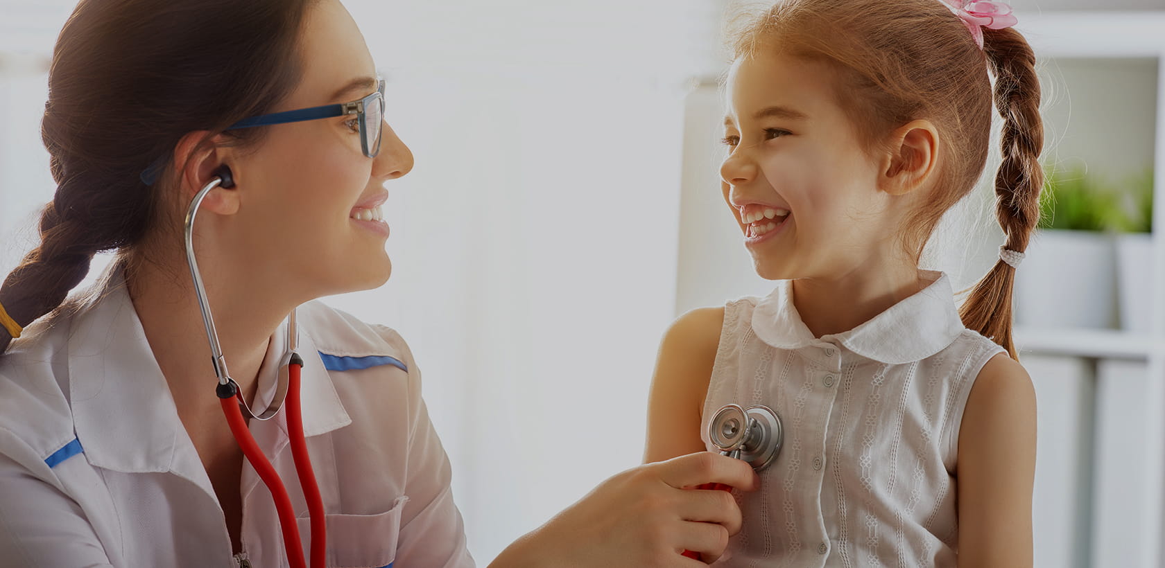 Smiling pediatrician checking a happy girl.